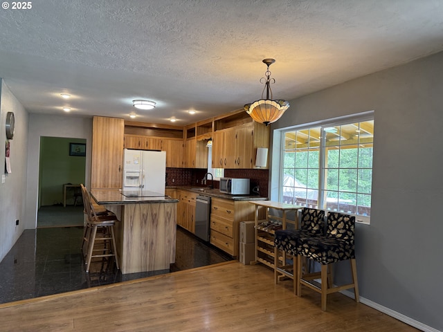 31431 Fairview Rd, Rainier, OR 97048 - kitchen featuring appliances with stainless steel finishes, a sink, dark countertops, tasteful backsplash, and a kitchen bar