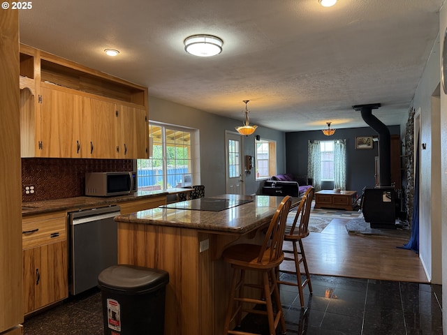 31431 Fairview Rd, Rainier, OR 97048 - kitchen with appliances with stainless steel finishes, open floor plan, a center island, a breakfast bar area, and a wood stove