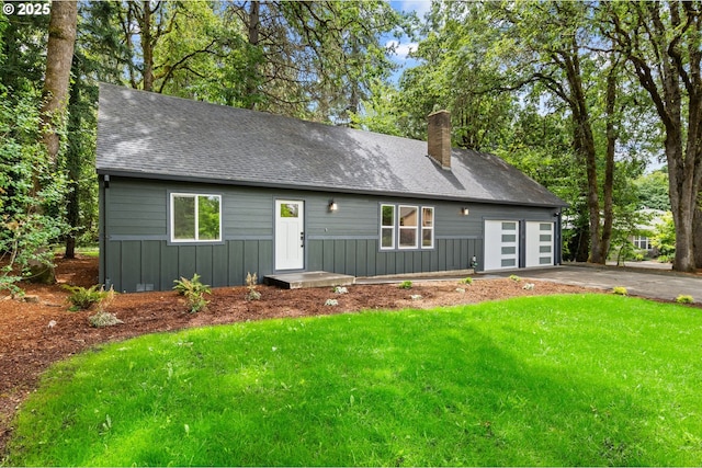 18240 SW Jay St, Beaverton, OR 97003 - view of front of house with board and batten siding, a chimney, a front lawn, and driveway