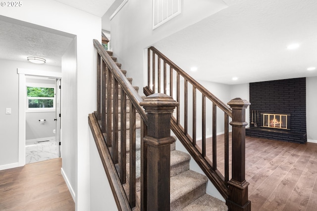 18240 SW Jay St, Beaverton, OR 97003 - stairs with wood finished floors, a brick fireplace, a textured ceiling, and recessed lighting