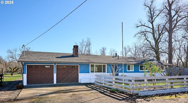 ranch-style house with a fenced front yard, driveway, a chimney, and a garage