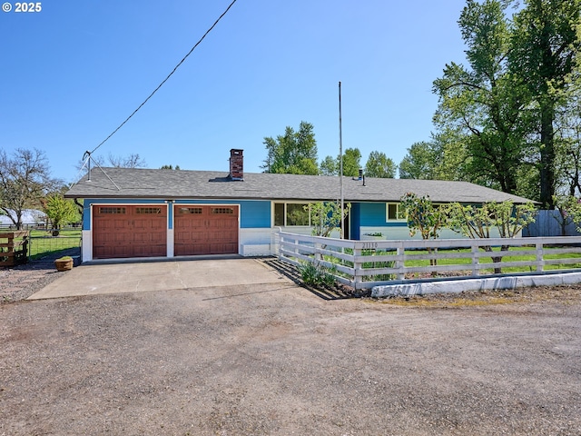 ranch-style house featuring a chimney, a garage, a shingled roof, and fence private yard