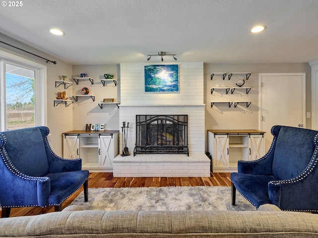 living area with recessed lighting, a fireplace, a textured ceiling, and wood finished floors