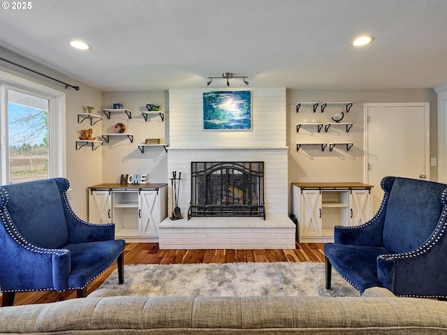 living room with a textured ceiling, wood finished floors, a fireplace, and recessed lighting