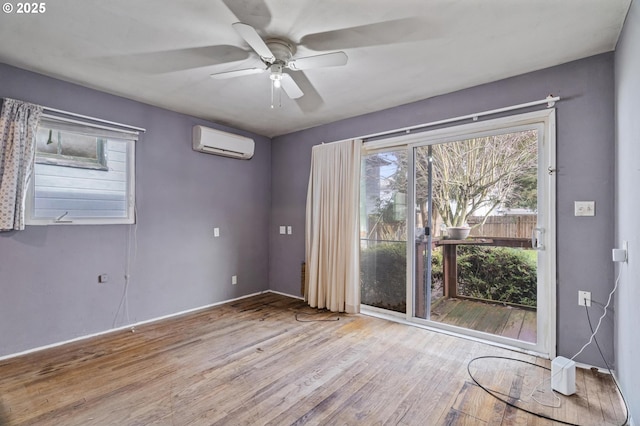 spare room with a wall unit AC, ceiling fan, and light wood-type flooring