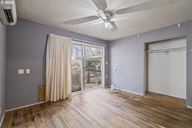 unfurnished bedroom featuring a closet, hardwood / wood-style flooring, ceiling fan, access to exterior, and an AC wall unit