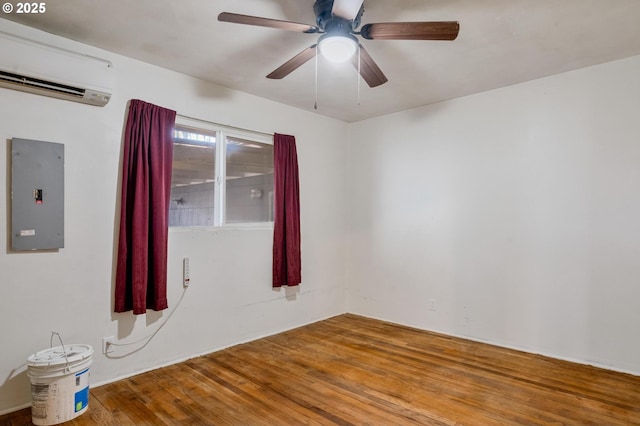 unfurnished room with wood-type flooring, a wall unit AC, ceiling fan, and electric panel