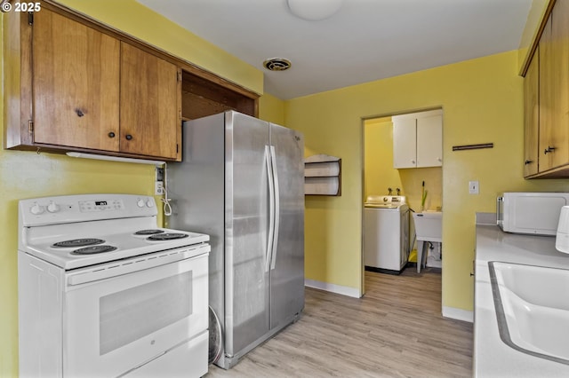 kitchen with white appliances, washer / dryer, sink, and light wood-type flooring