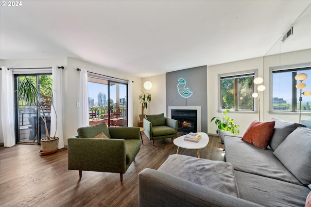 living area with wood finished floors, healthy amount of natural light, a lit fireplace, and a city view