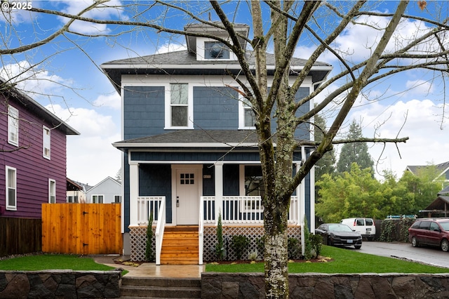 traditional style home with fence, covered porch, and roof with shingles