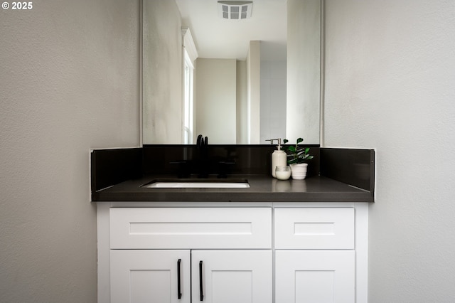 bathroom featuring vanity, a textured wall, and visible vents