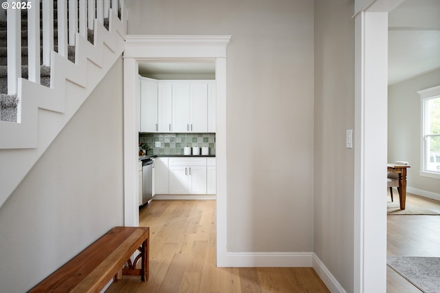 hallway featuring stairs, light wood-style flooring, and baseboards