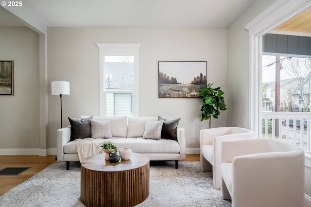 living room with wood finished floors, a healthy amount of sunlight, visible vents, and baseboards