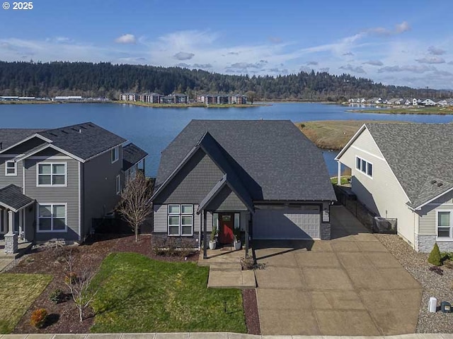 view of front of home with concrete driveway, a view of trees, and a water view