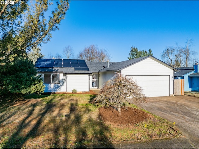 ranch-style house with a garage, a front yard, and solar panels