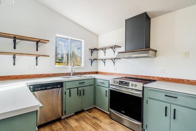 kitchen with lofted ceiling, sink, wall chimney range hood, appliances with stainless steel finishes, and a textured ceiling