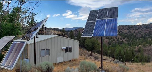 view of side of home featuring a mountain view and solar panels