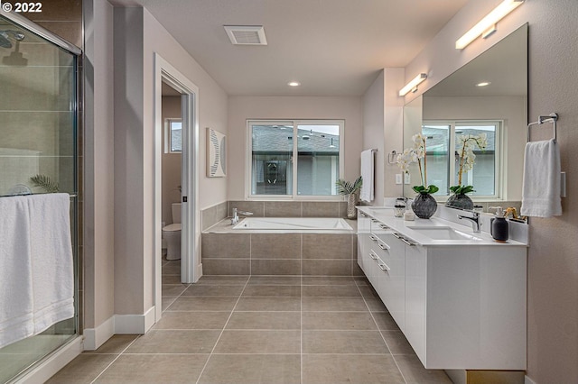 full bathroom with dual sinks, toilet, independent shower and bath, vanity with extensive cabinet space, and tile floors