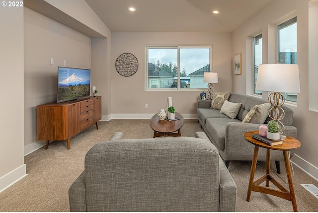 living room with a wealth of natural light, light carpet, and vaulted ceiling