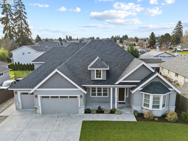 view of front of house featuring an attached garage, stone siding, driveway, roof with shingles, and a front yard