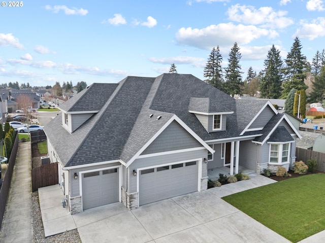 view of front of home featuring fence, stone siding, concrete driveway, roof with shingles, and a front yard