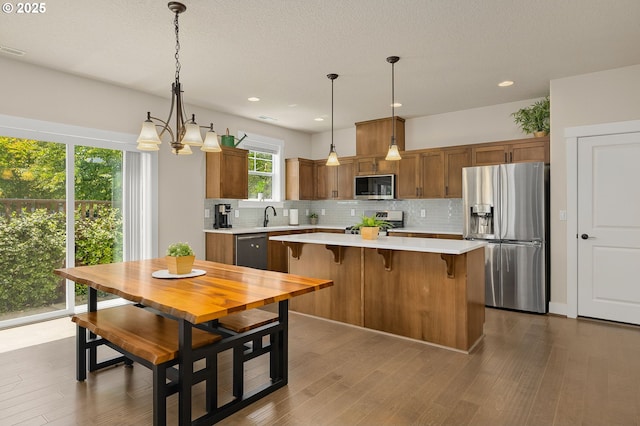 13193 SW Aubergine Ter, Sherwood, OR 97140 - kitchen with appliances with stainless steel finishes, light countertops, backsplash, brown cabinetry, and a kitchen island