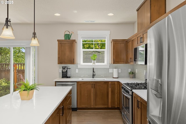 13193 SW Aubergine Ter, Sherwood, OR 97140 - kitchen featuring stainless steel appliances, light countertops, dark wood-style flooring, backsplash, and brown cabinetry