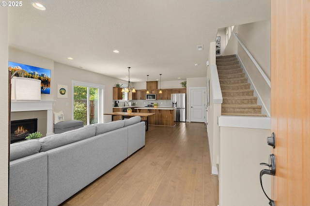 13193 SW Aubergine Ter, Sherwood, OR 97140 - living area featuring wood finished floors, recessed lighting, a tile fireplace, stairway, and a chandelier