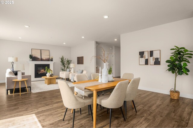 dining room with recessed lighting, baseboards, a glass covered fireplace, and wood finished floors