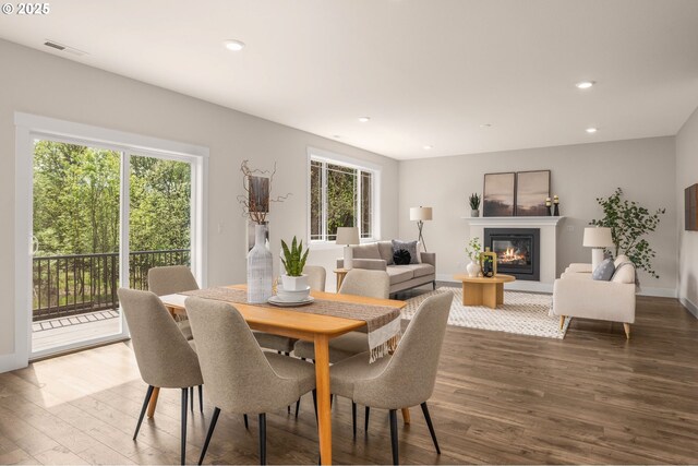 dining area featuring a glass covered fireplace, recessed lighting, wood finished floors, and visible vents
