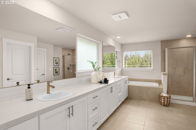 bathroom with a garden tub, double vanity, tile patterned floors, a shower stall, and a sink