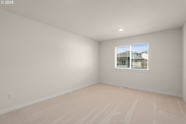 unfurnished room featuring baseboards, light colored carpet, and visible vents