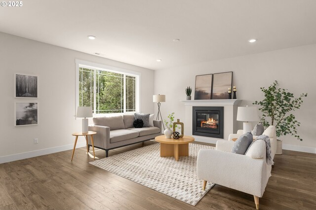 living room featuring a glass covered fireplace, baseboards, recessed lighting, and wood finished floors