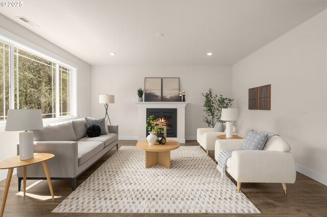 living room with visible vents, a glass covered fireplace, wood finished floors, baseboards, and recessed lighting