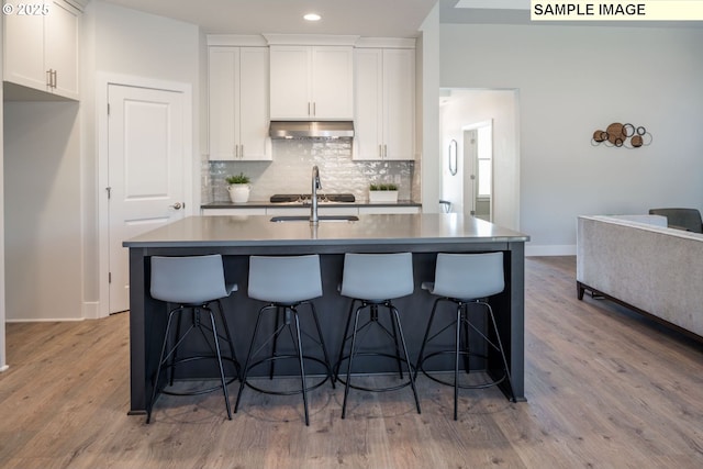 8119 N Hargrave St, Camas, WA 98607 - kitchen with white cabinetry, tasteful backsplash, a center island with sink, under cabinet range hood, and light wood-style floors