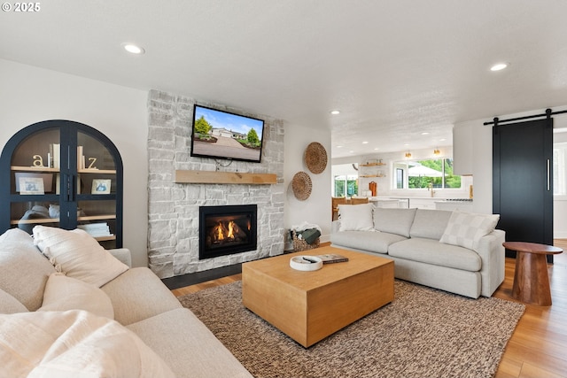 living area with recessed lighting, a barn door, and light wood-style flooring