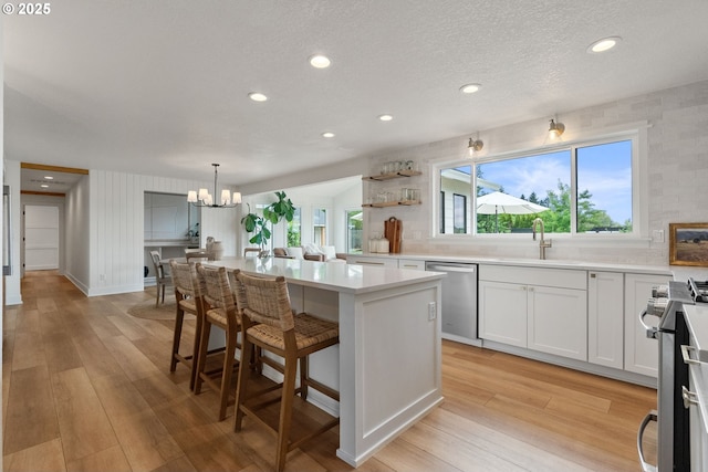 kitchen featuring a center island, light countertops, a sink, appliances with stainless steel finishes, and a notable chandelier