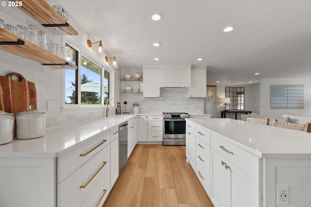 kitchen featuring appliances with stainless steel finishes, tasteful backsplash, open shelves, a sink, and recessed lighting
