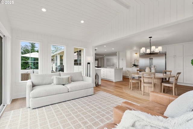 living room with lofted ceiling, recessed lighting, light wood-style flooring, and a chandelier