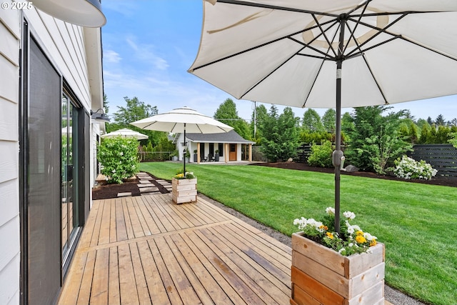 wooden terrace featuring an outdoor structure, fence, and a yard