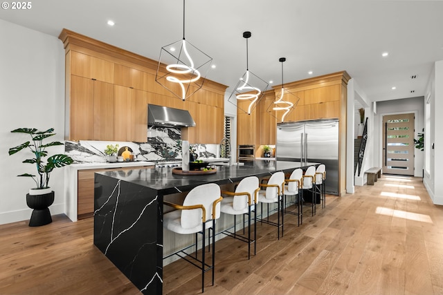 NE 43rd Cir Lot 5, Camas, WA 98607 - kitchen with ventilation hood, stainless steel appliances, modern cabinets, light wood-type flooring, and decorative backsplash