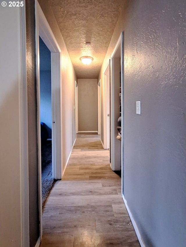 hallway featuring a textured ceiling and light wood-type flooring