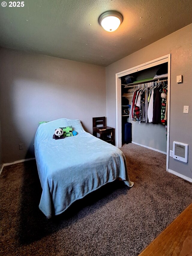 bedroom with heating unit, a closet, a textured ceiling, and carpet