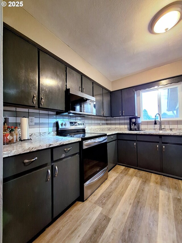 kitchen with sink, a textured ceiling, light wood-type flooring, appliances with stainless steel finishes, and decorative backsplash