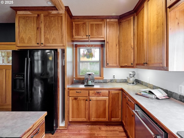 111 5th St, Silverton, OR 97381 - kitchen featuring black fridge, dishwasher, light wood finished floors, brown cabinets, and light countertops