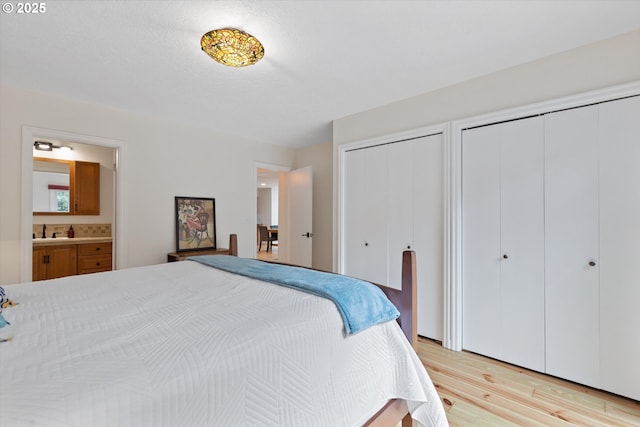 2245 SW Martha St, Portland, OR 97239 - bedroom featuring multiple closets, light wood-style flooring, and ensuite bath