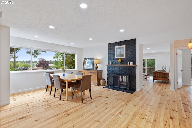 2245 SW Martha St, Portland, OR 97239 - dining space with light wood finished floors, recessed lighting, a brick fireplace, and a textured ceiling