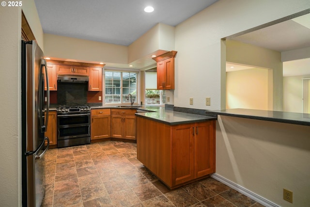 533 Fountain Ct, Keizer, OR 97303 - kitchen featuring stainless steel appliances, under cabinet range hood, a peninsula, brown cabinets, and dark stone finish flooring