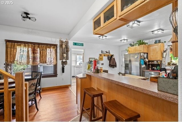 680 S Alfalfa St, Heppner, OR 97836 - kitchen featuring stainless steel appliances, light wood-style floors, a breakfast bar, glass insert cabinets, and a peninsula