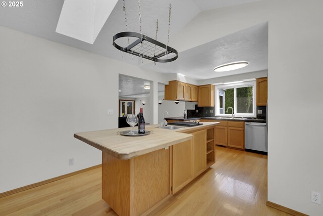 kitchen with a sink, light wood-style floors, dishwasher, baseboards, and tasteful backsplash